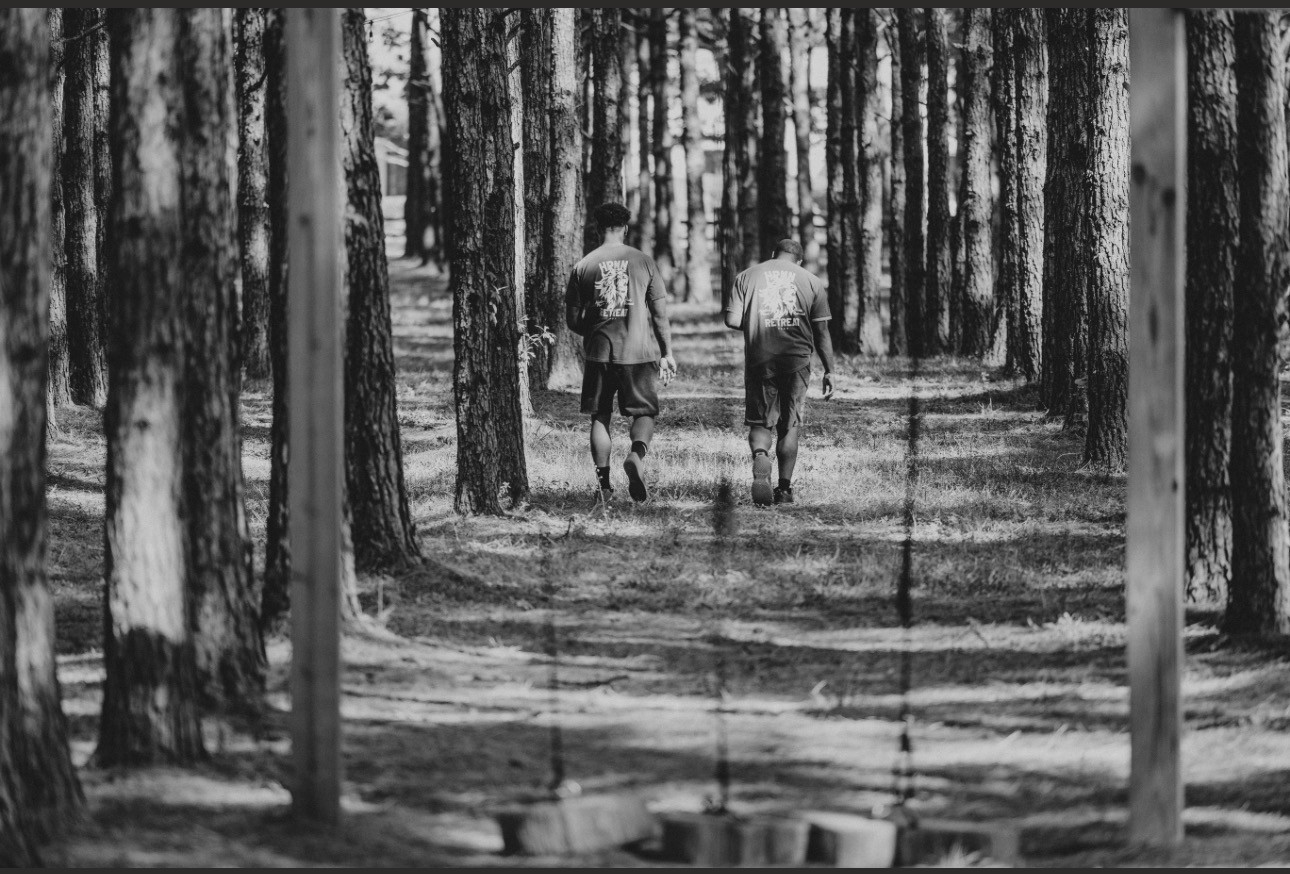 Two men walking through a pine forest