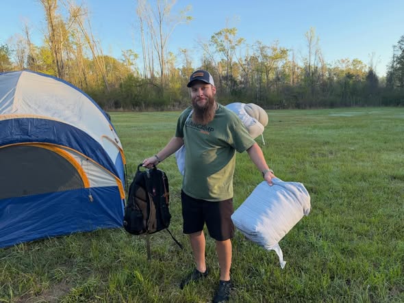 Camper arriving with gear beside a tent